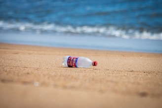 plastic waste pacific ocean white and blue plastic bottle on beach shore during daytime
