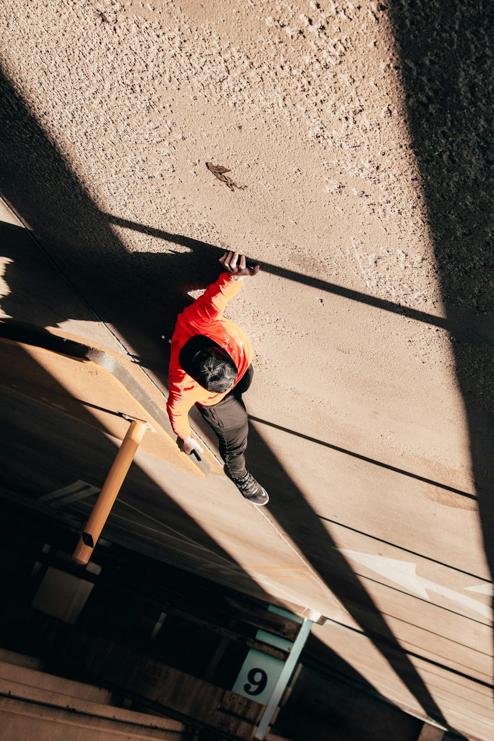 man in red hoodie and gray pants holding brown wooden stick