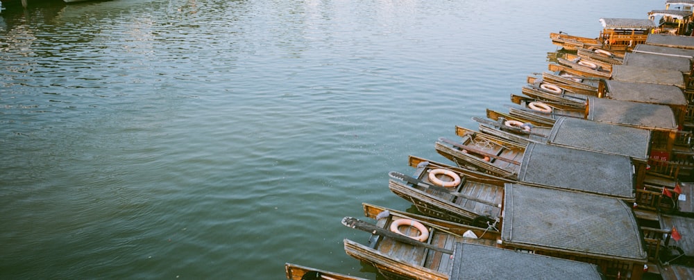 uma fileira de barcos de madeira flutuando no topo de um rio