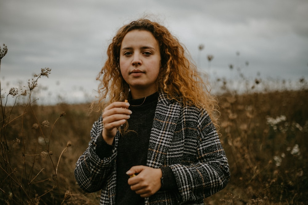 woman in black and white plaid long sleeve shirt standing on brown grass field during daytime