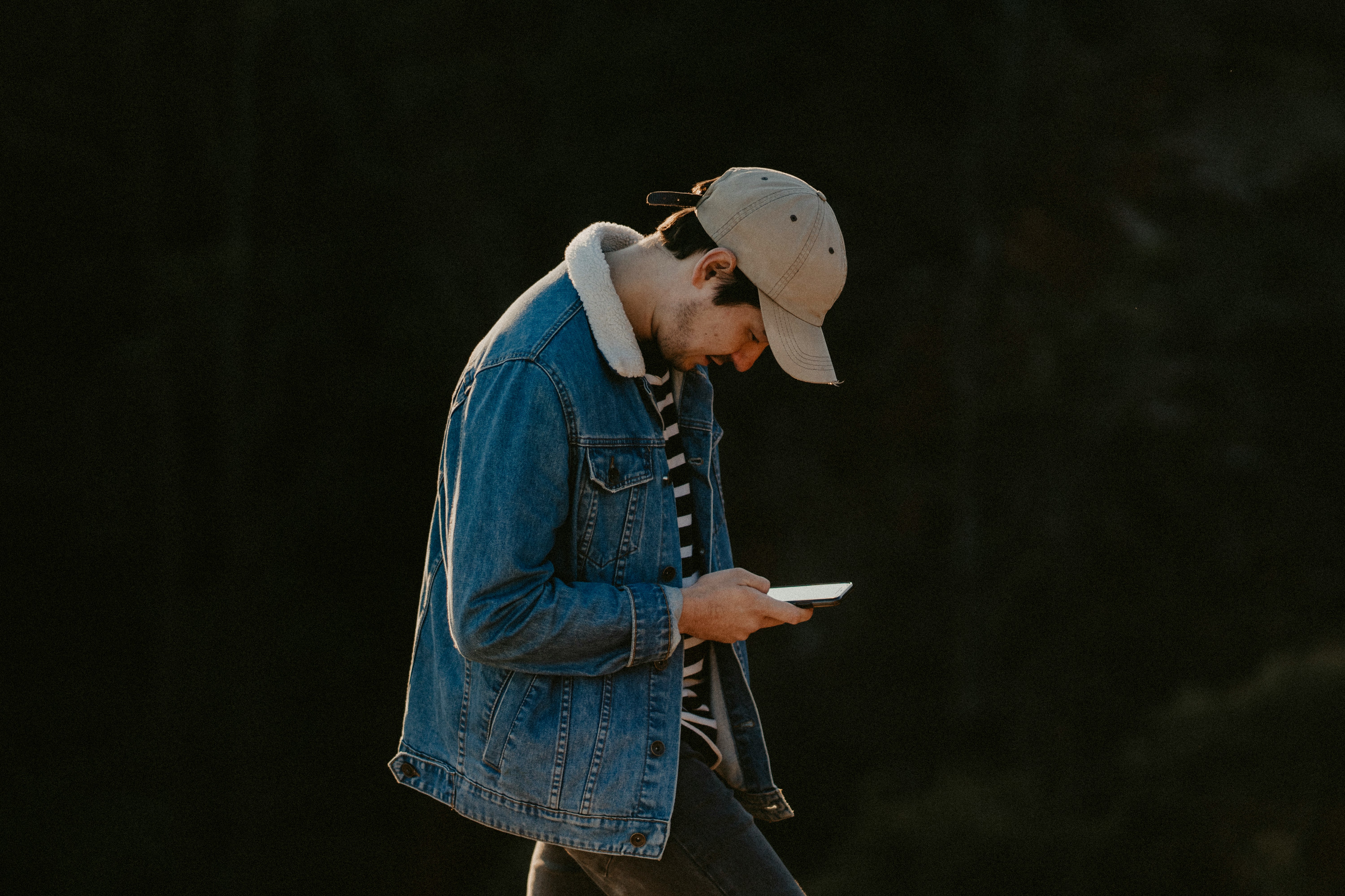 woman in blue denim jacket and brown hat holding white book