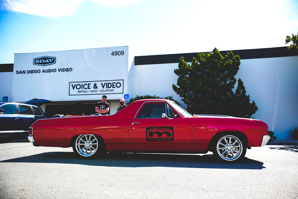 red coupe parked near white box truck