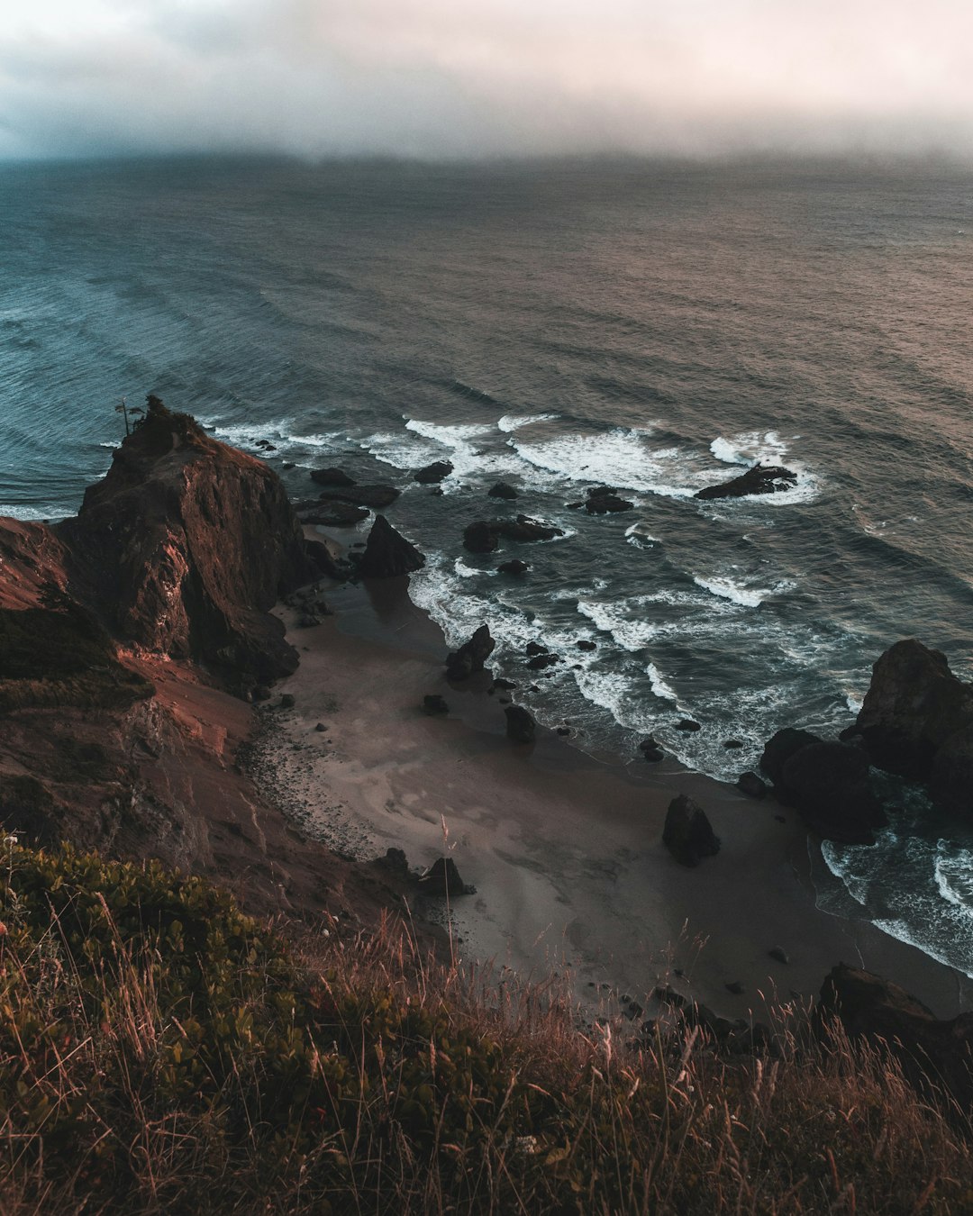 brown rocky mountain beside sea during daytime