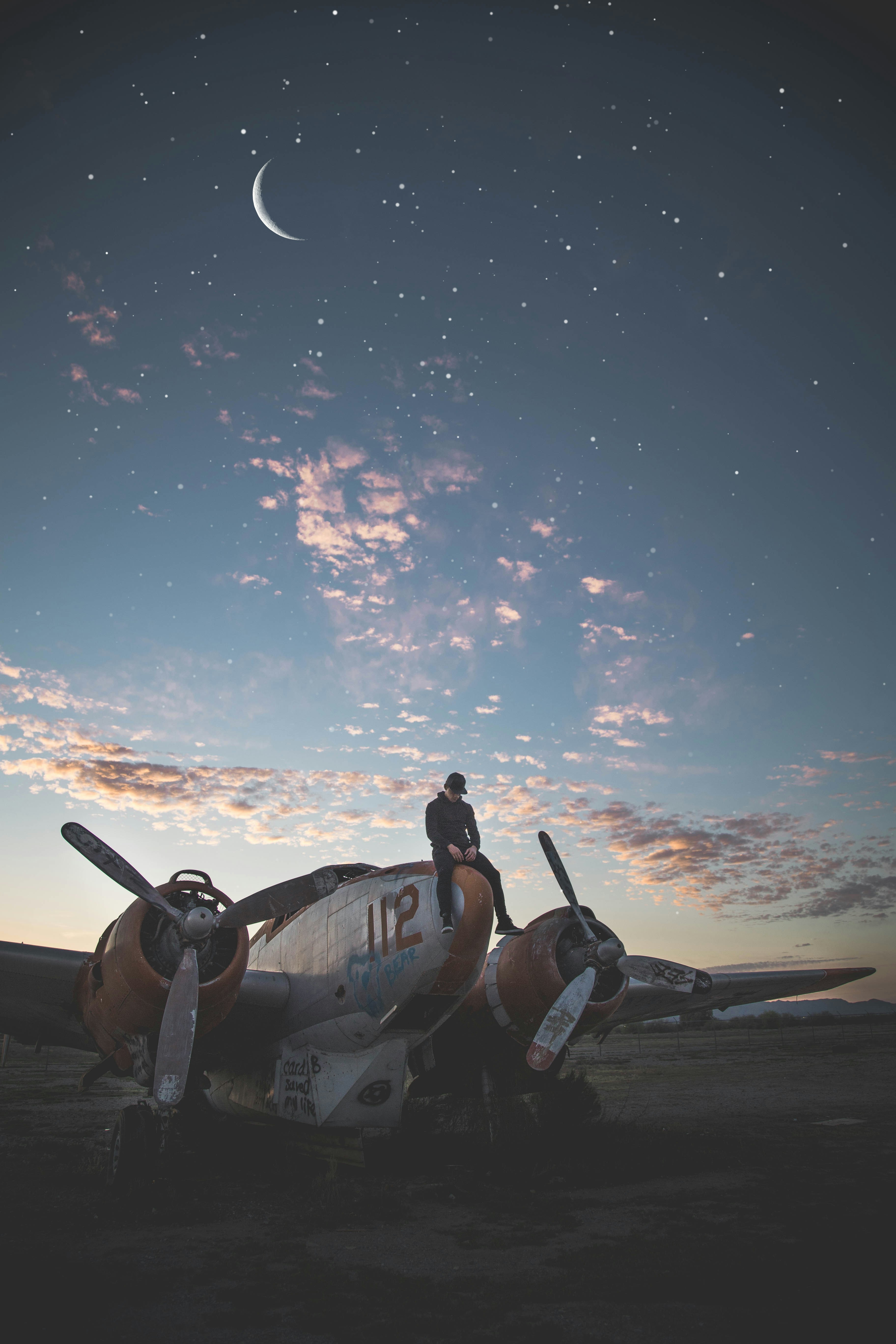 Model sitting on a scrap airplane with starry sky 