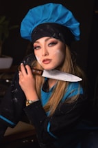 A friendly culinary instructor smiling while holding a chef's knife in a professional kitchen setting.