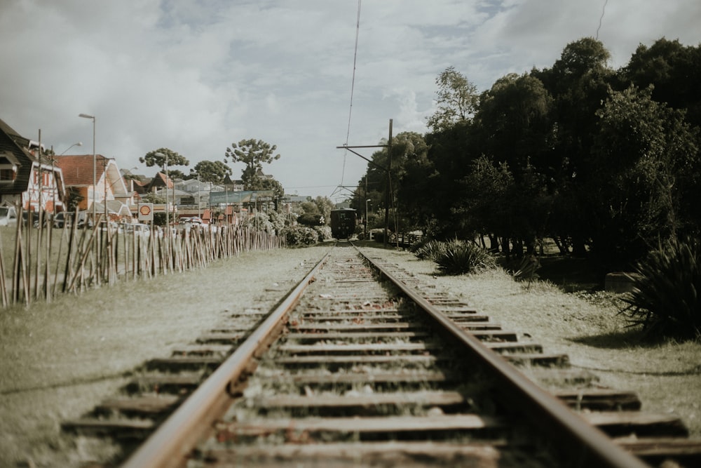 train rail tracks near trees and houses during daytime