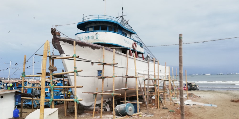 white and blue boat on brown sand during daytime