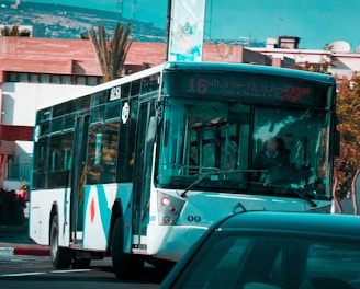 a city bus driving down a street next to a car