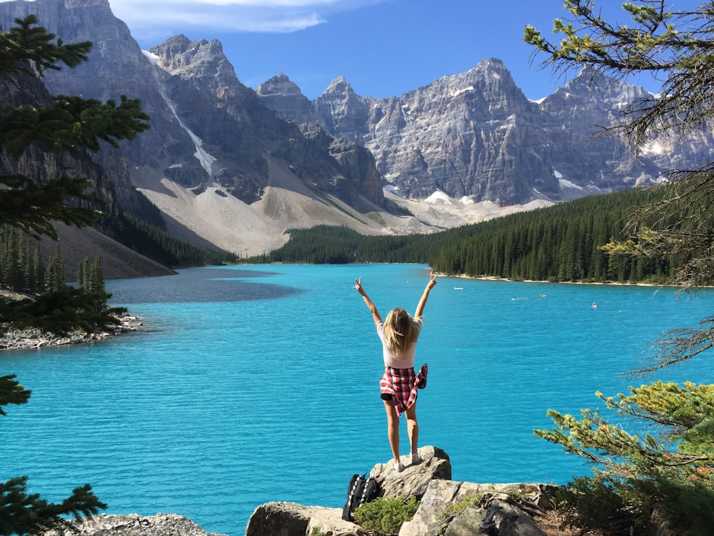 woman in pink bikini standing on rock near body of water during daytime