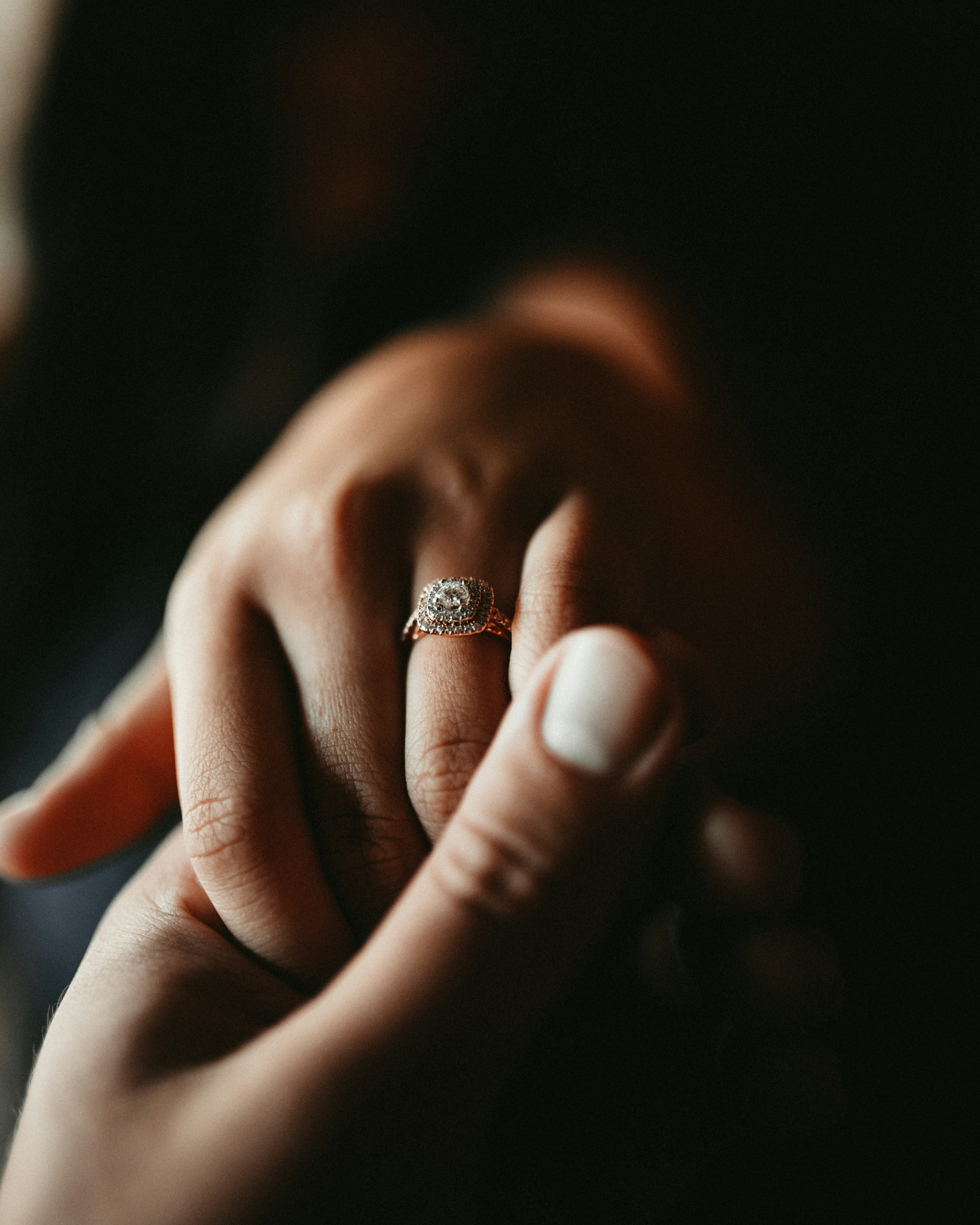 Man holds hand of fiancé with ring on finger.