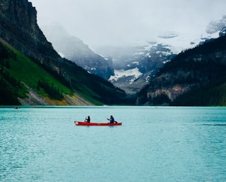 person riding red boat on body of water during daytime