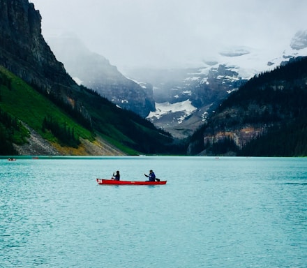 person riding red boat on body of water during daytime