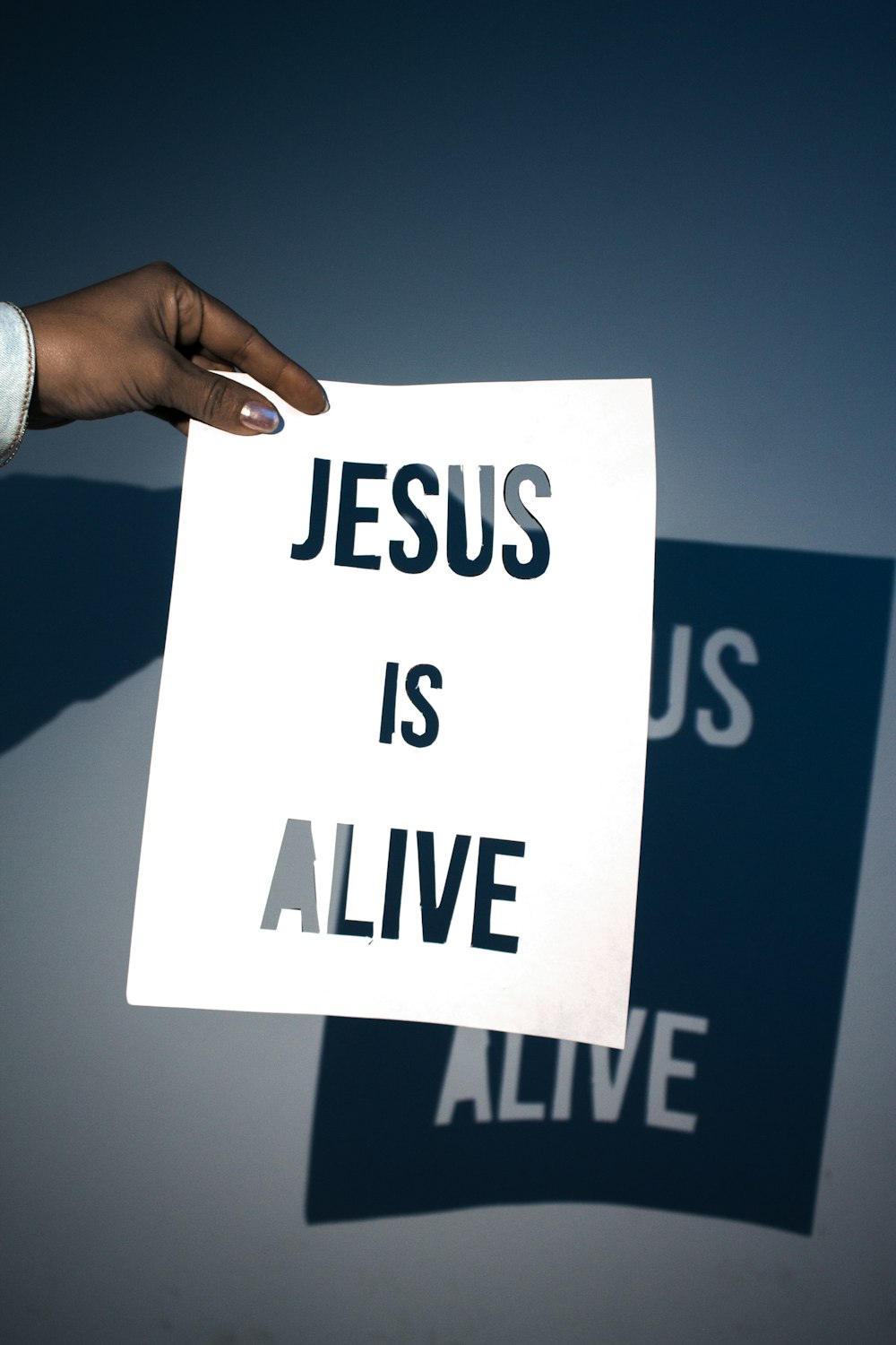 a person holding a piece of paper with the words jesus is alive on it