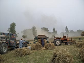 red and blue tractor on green grass field under white clouds during daytime