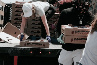 man in white t-shirt and white pants holding black and white box