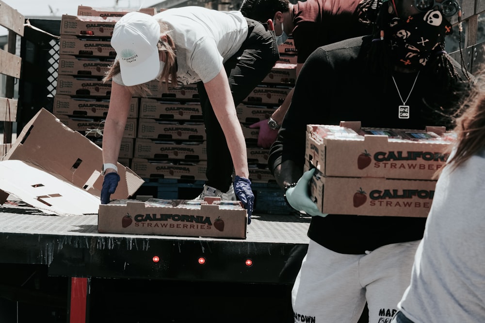 man in white t-shirt and white pants holding black and white box