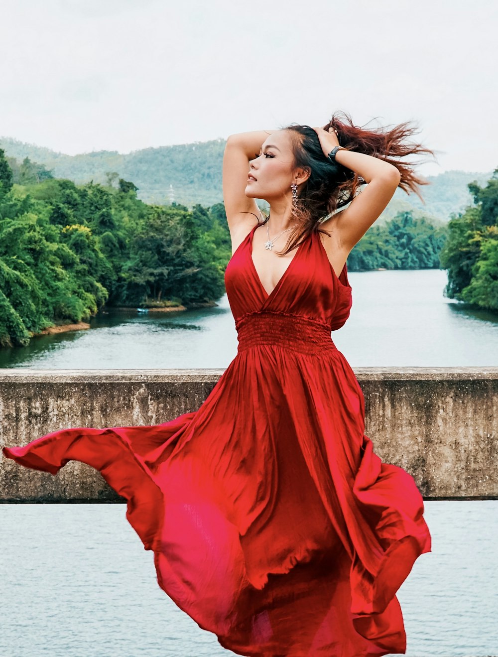 woman in red sleeveless dress standing near body of water during daytime