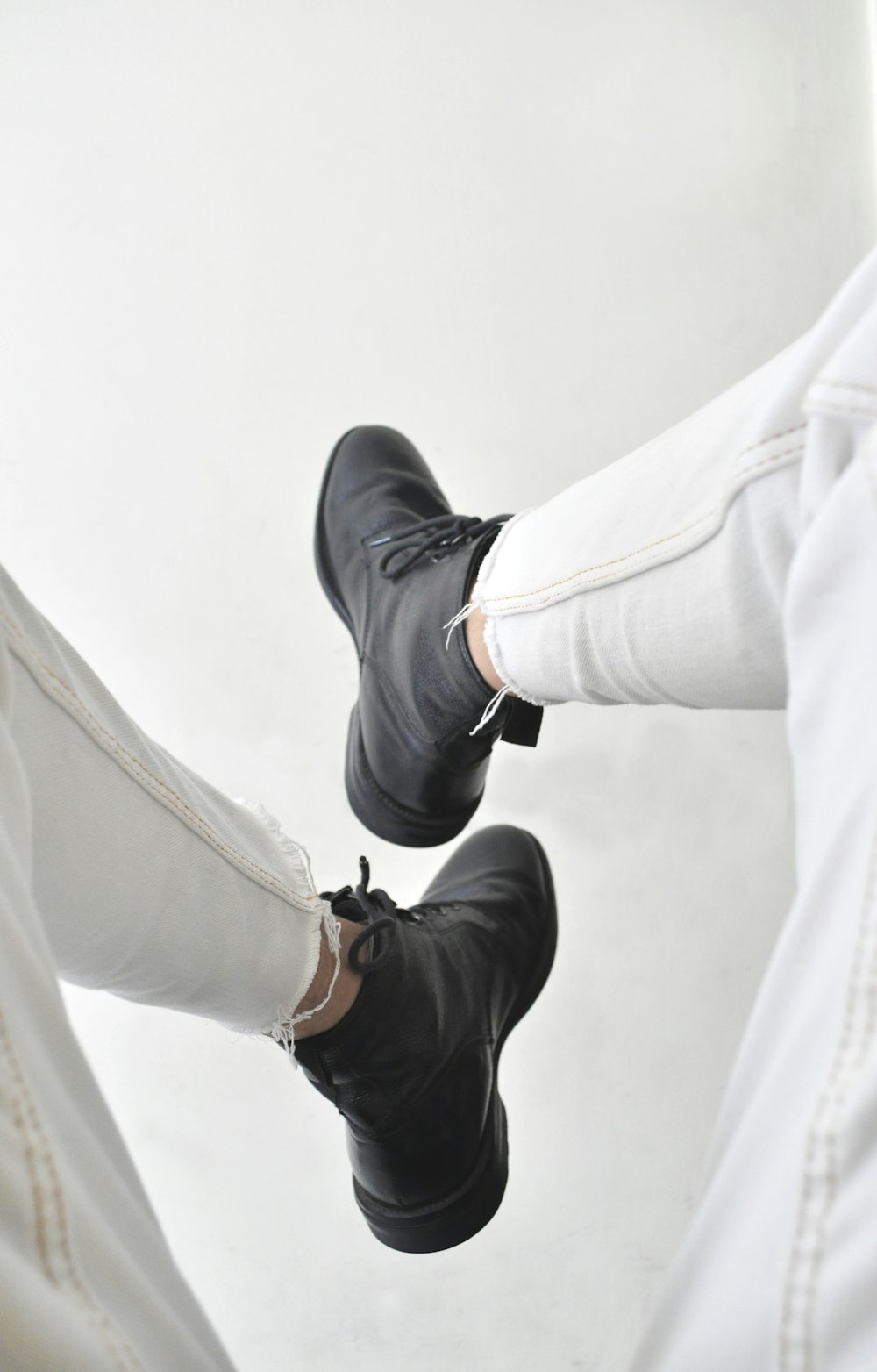 person in black leather shoes and white pants