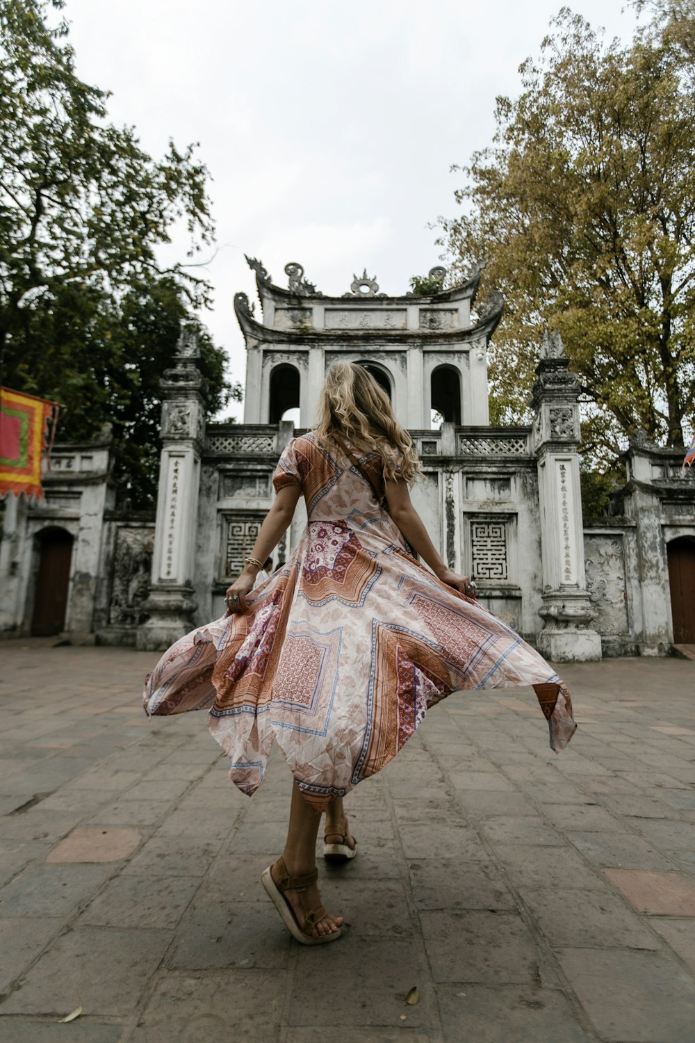 woman in pink dress walking on sidewalk during daytime