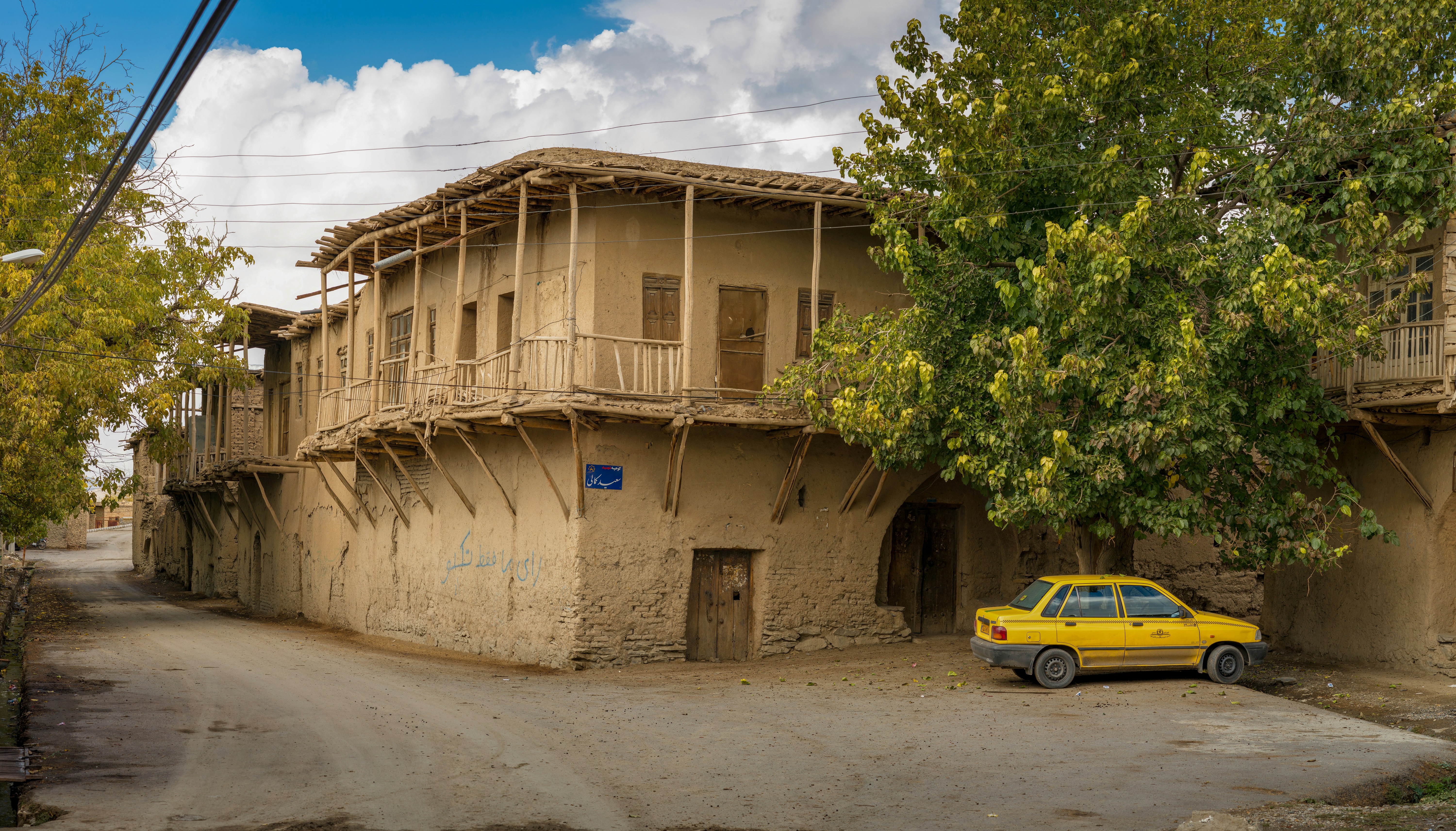 yellow car parked beside brown concrete building during daytime
