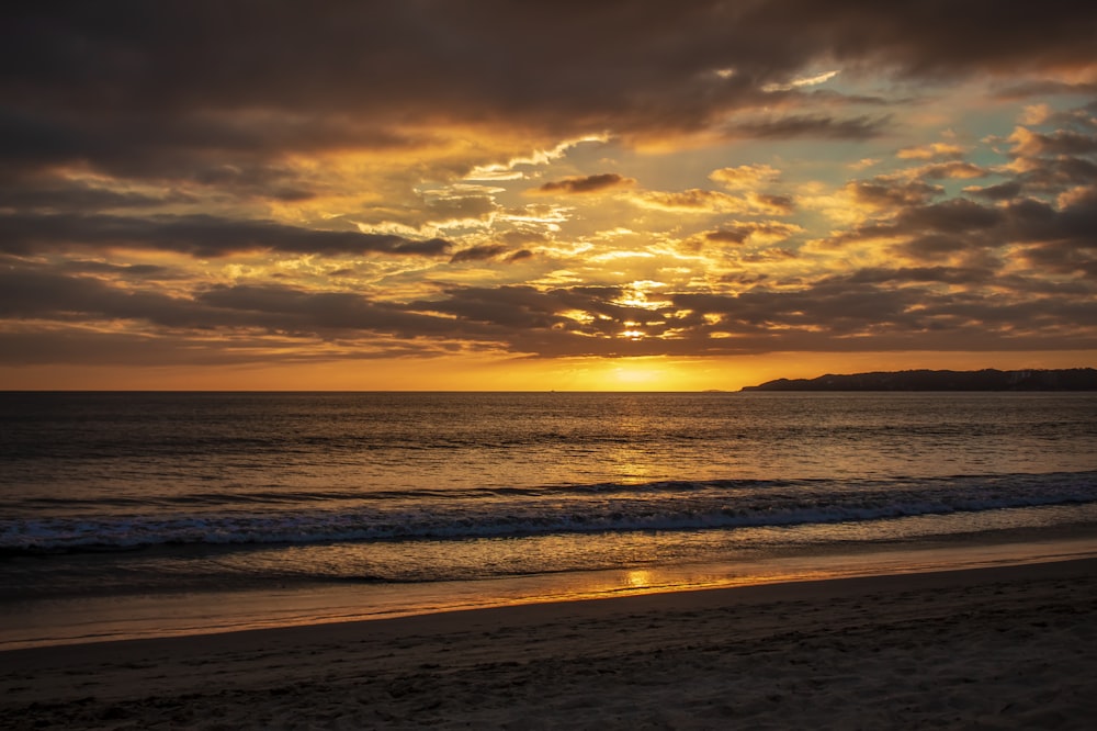 sea waves crashing on shore during sunset