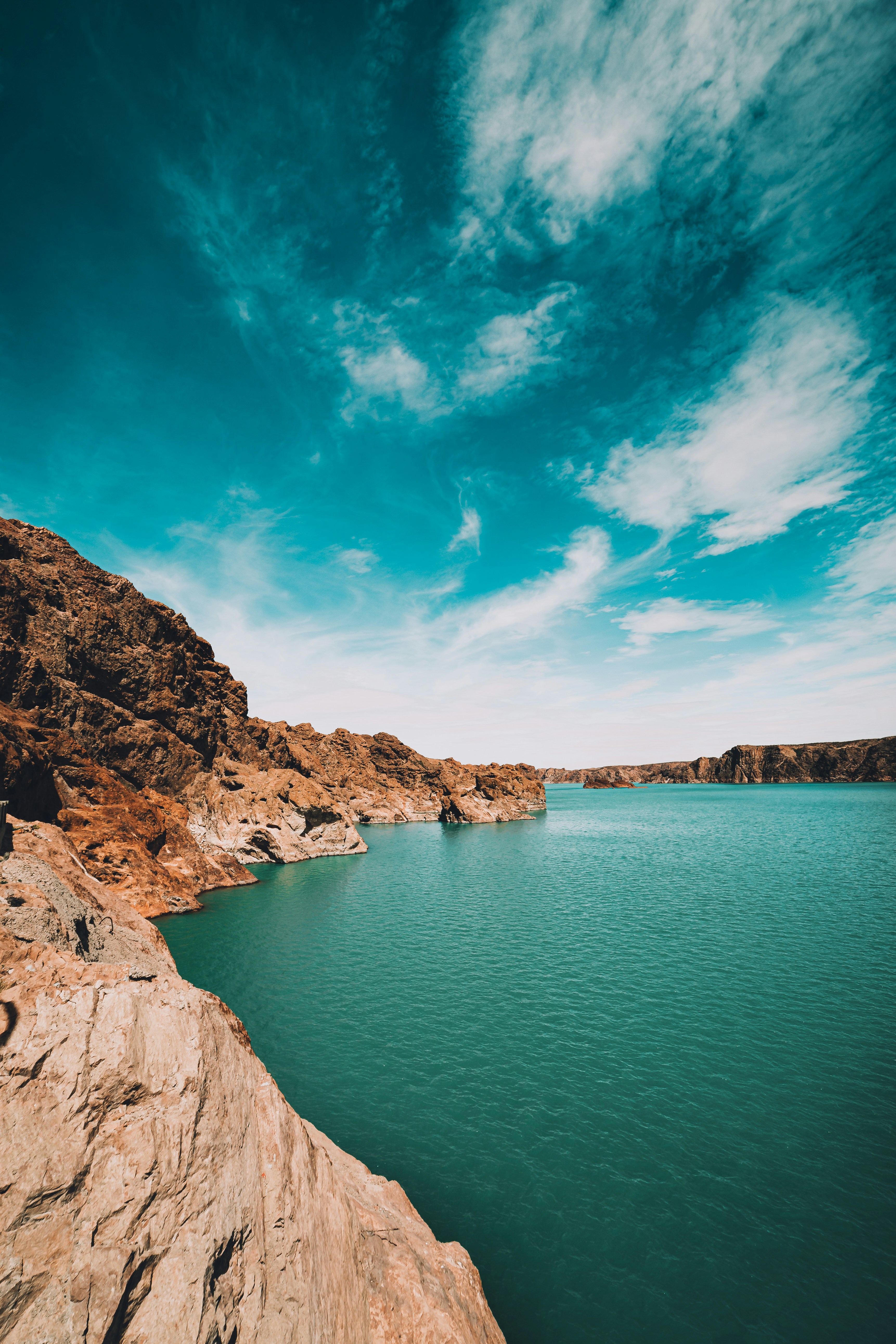 brown rocky mountain beside blue sea under blue sky during daytime