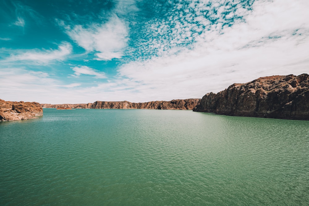 body of water near mountain under blue sky during daytime