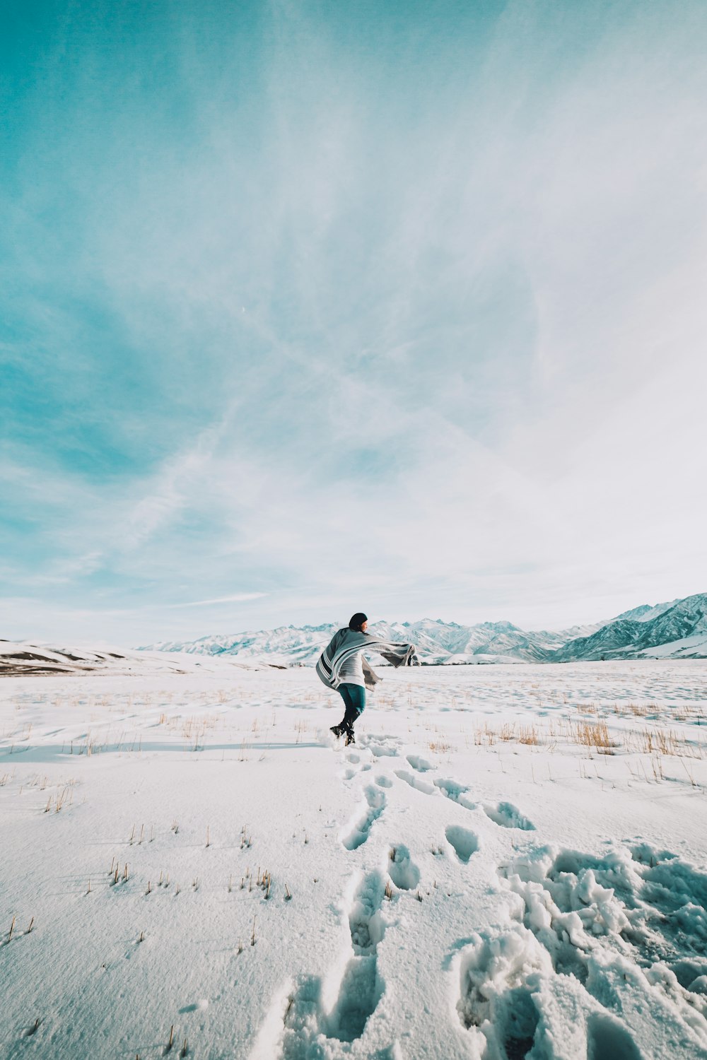 person in white jacket and black pants walking on snow covered field during daytime