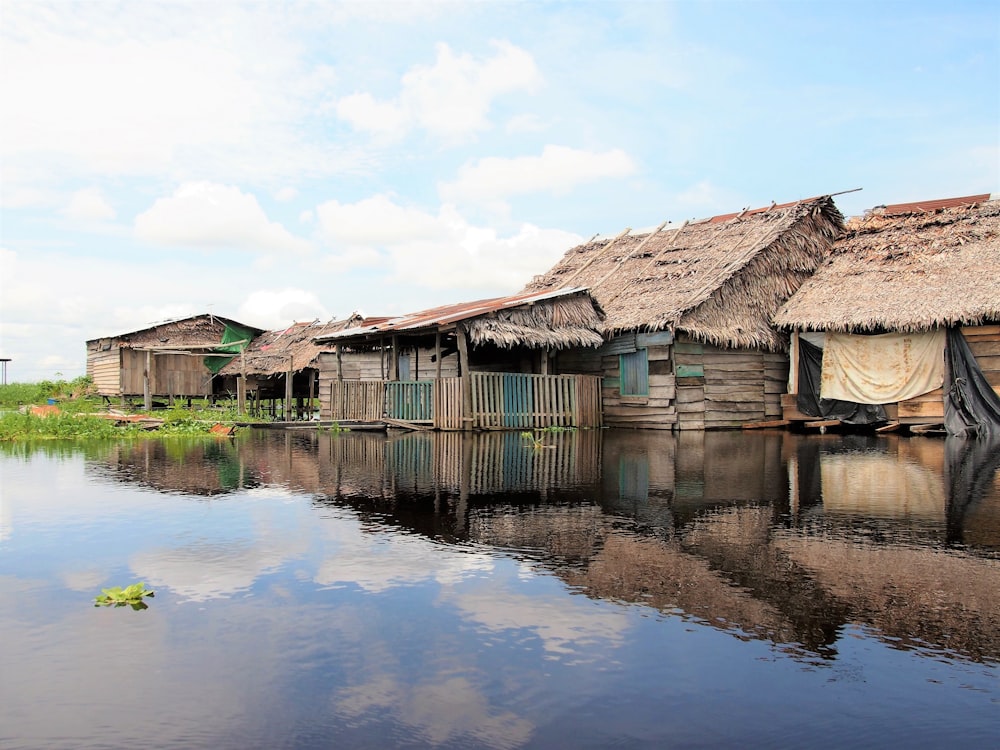 brown wooden house on water under blue sky during daytime