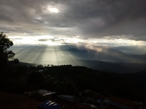 Sunlight breaking through dark clouds over a quiet mountain chapel