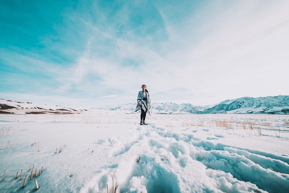 donna in giacca nera che cammina su terreno coperto di neve durante il giorno
