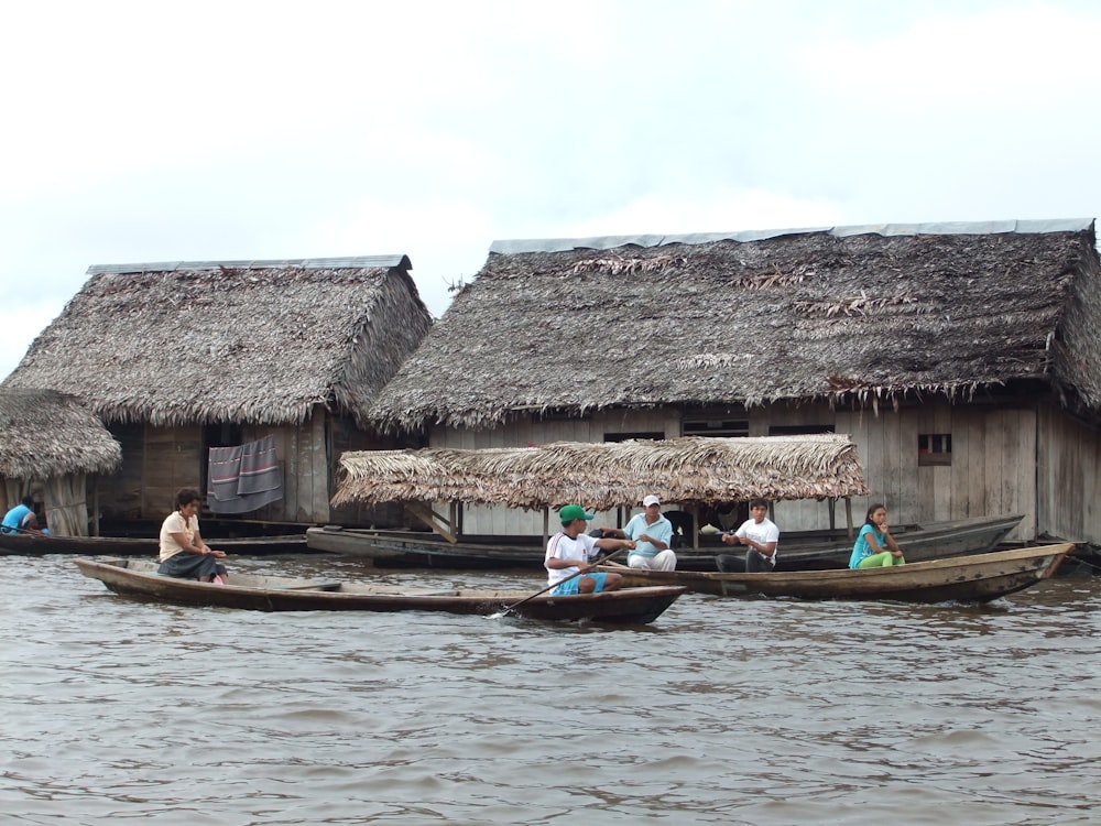 昼間、茶色の木造住宅の近くでボートに乗る人々