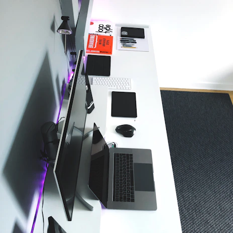A minimalist desk setup featuring coding books, a notebook, and a tablet.