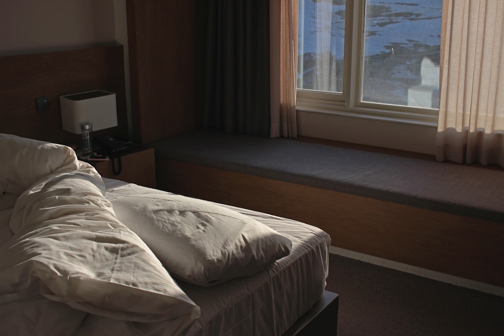 white bed linen near brown window curtain