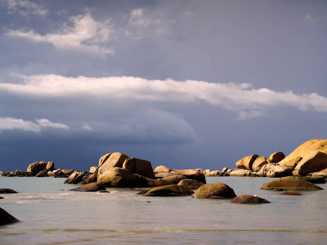 brown rocks on sea shore under cloudy sky during daytime