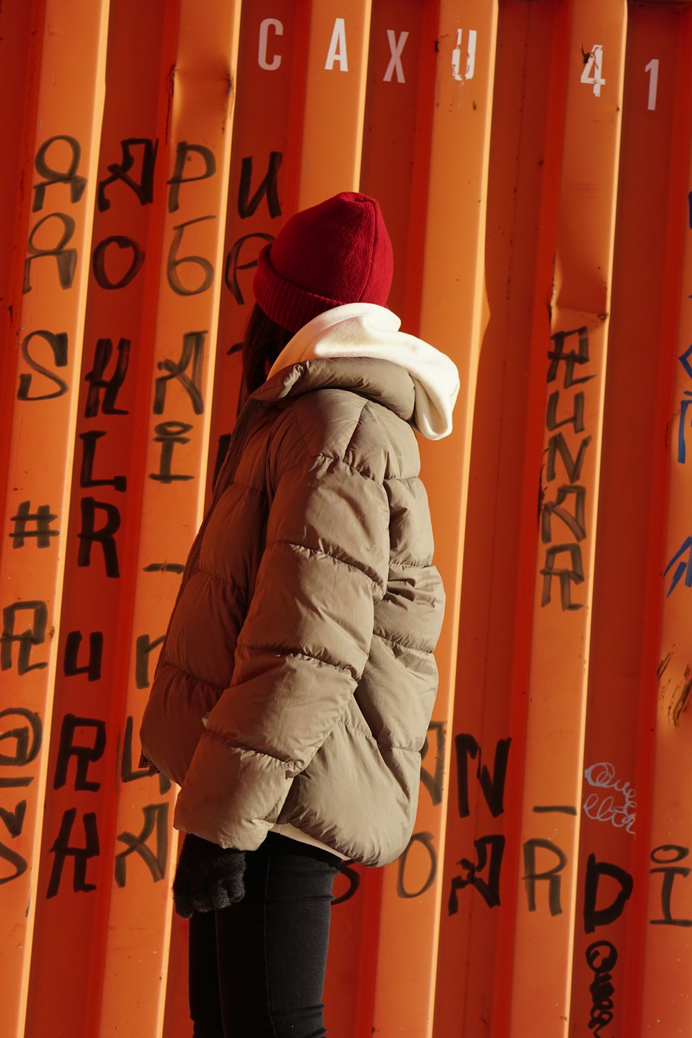 person in white bubble jacket standing beside yellow and red wall