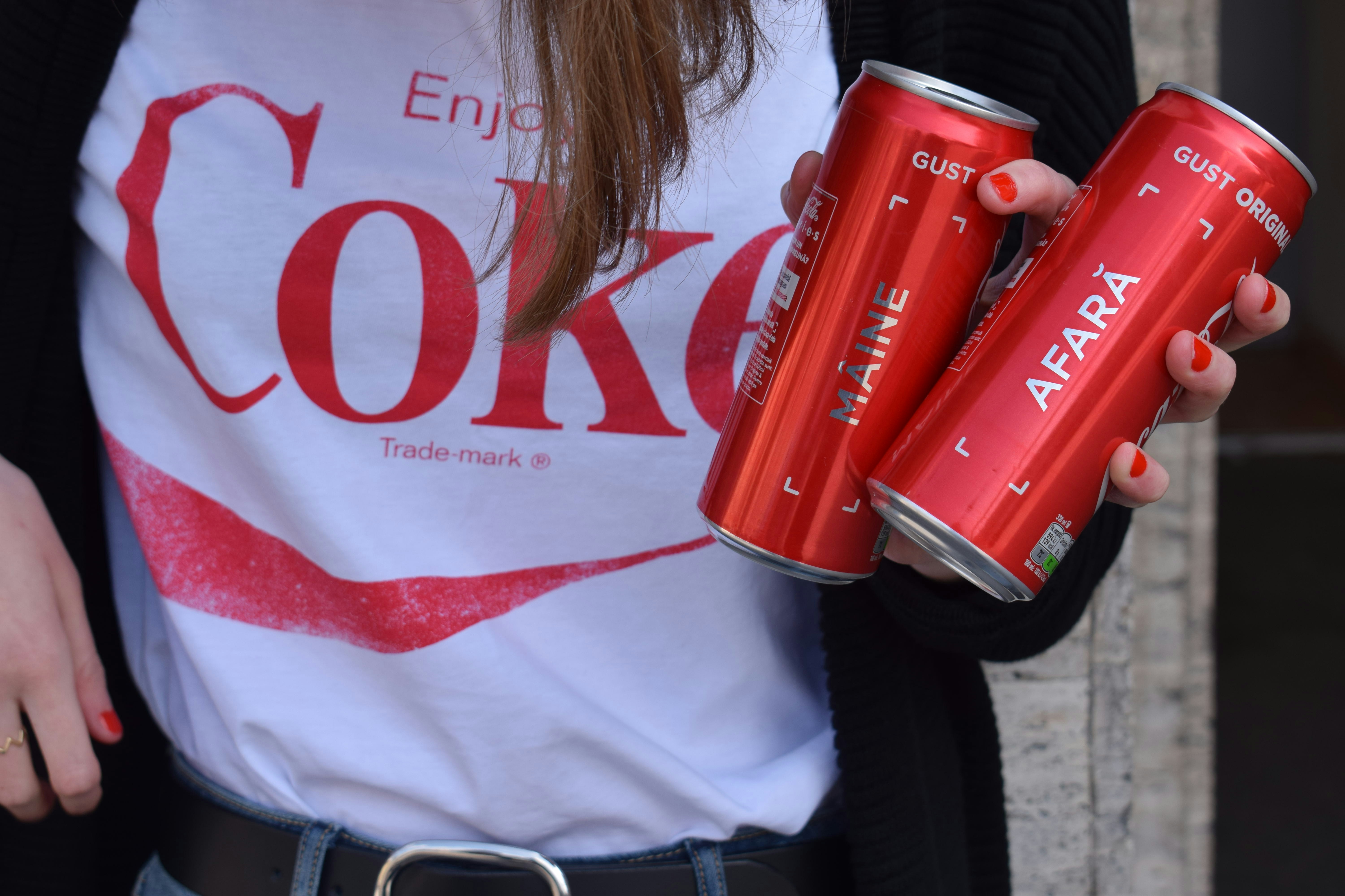 woman in white and red shirt holding coca cola can