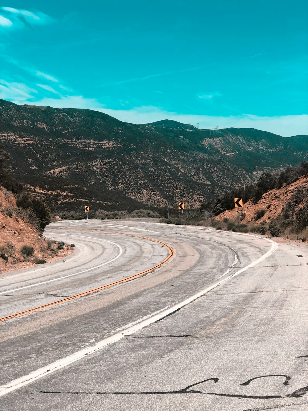 gray asphalt road near brown mountain under blue sky during daytime