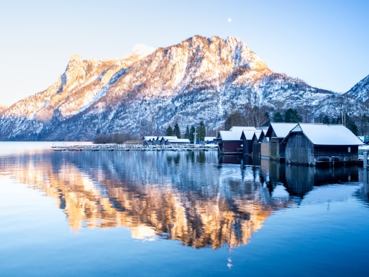 brown wooden house on lake near brown mountain during daytime in Ebensee Austria