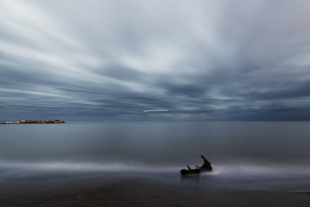 silhouette de 2 personnes assises sur le rivage de la plage pendant le coucher du soleil