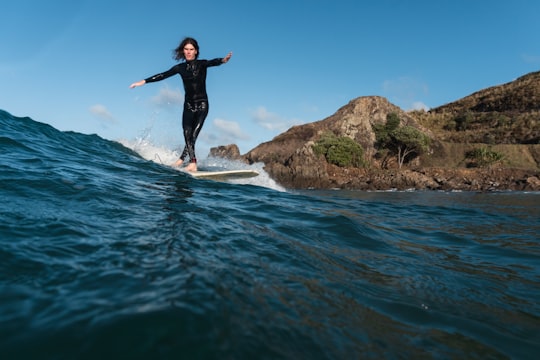 woman in black wetsuit surfing on water during daytime in Te Arai New Zealand