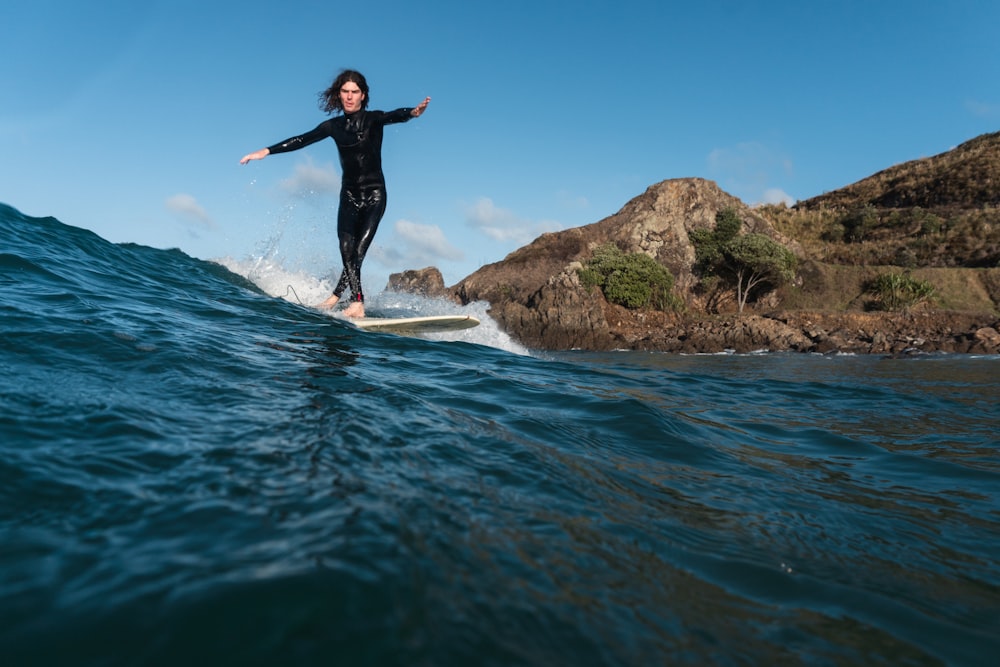 woman in black wetsuit surfing on water during daytime