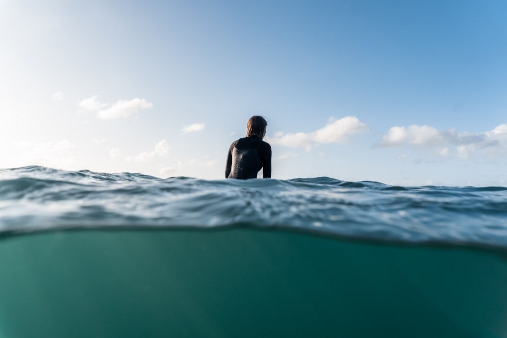 woman in black shirt sitting on sea water during daytime