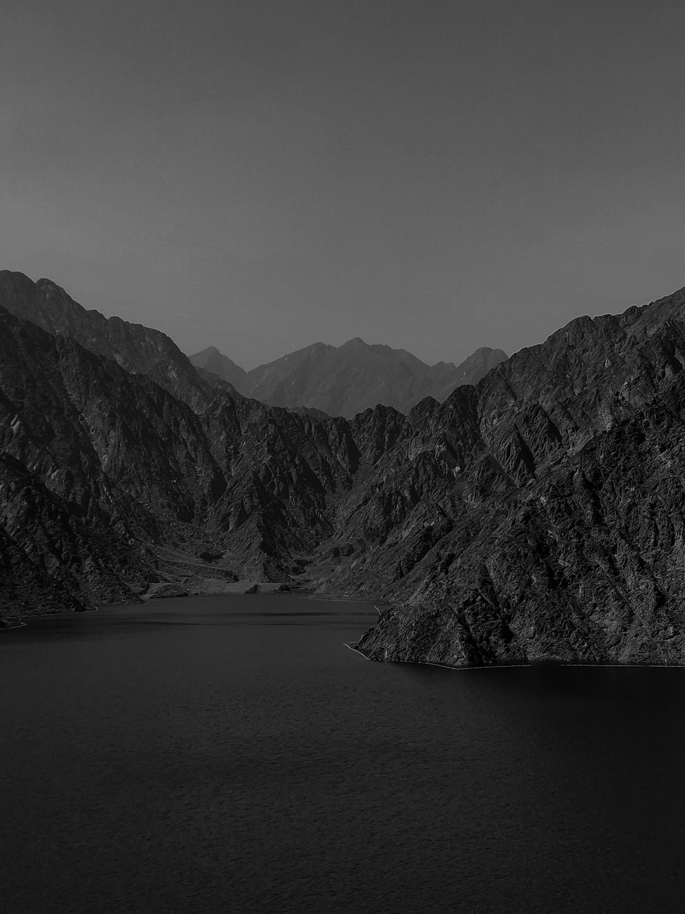 grayscale photo of mountains near body of water