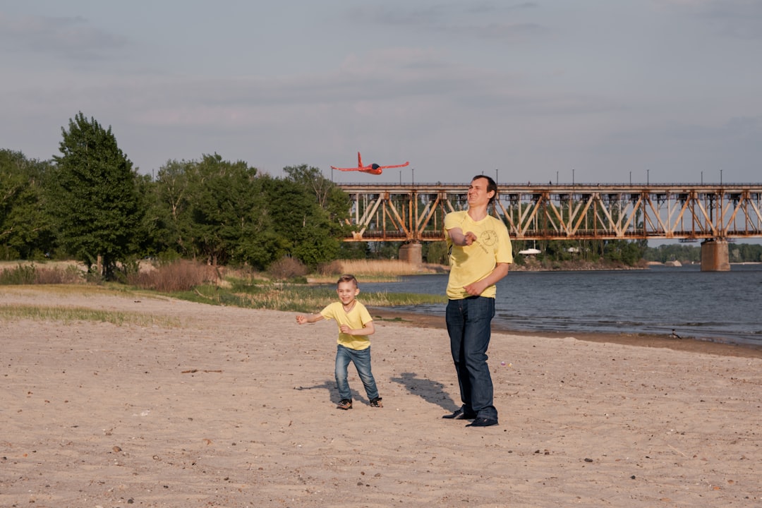 man in yellow polo shirt standing beside woman in black shirt near body of water during