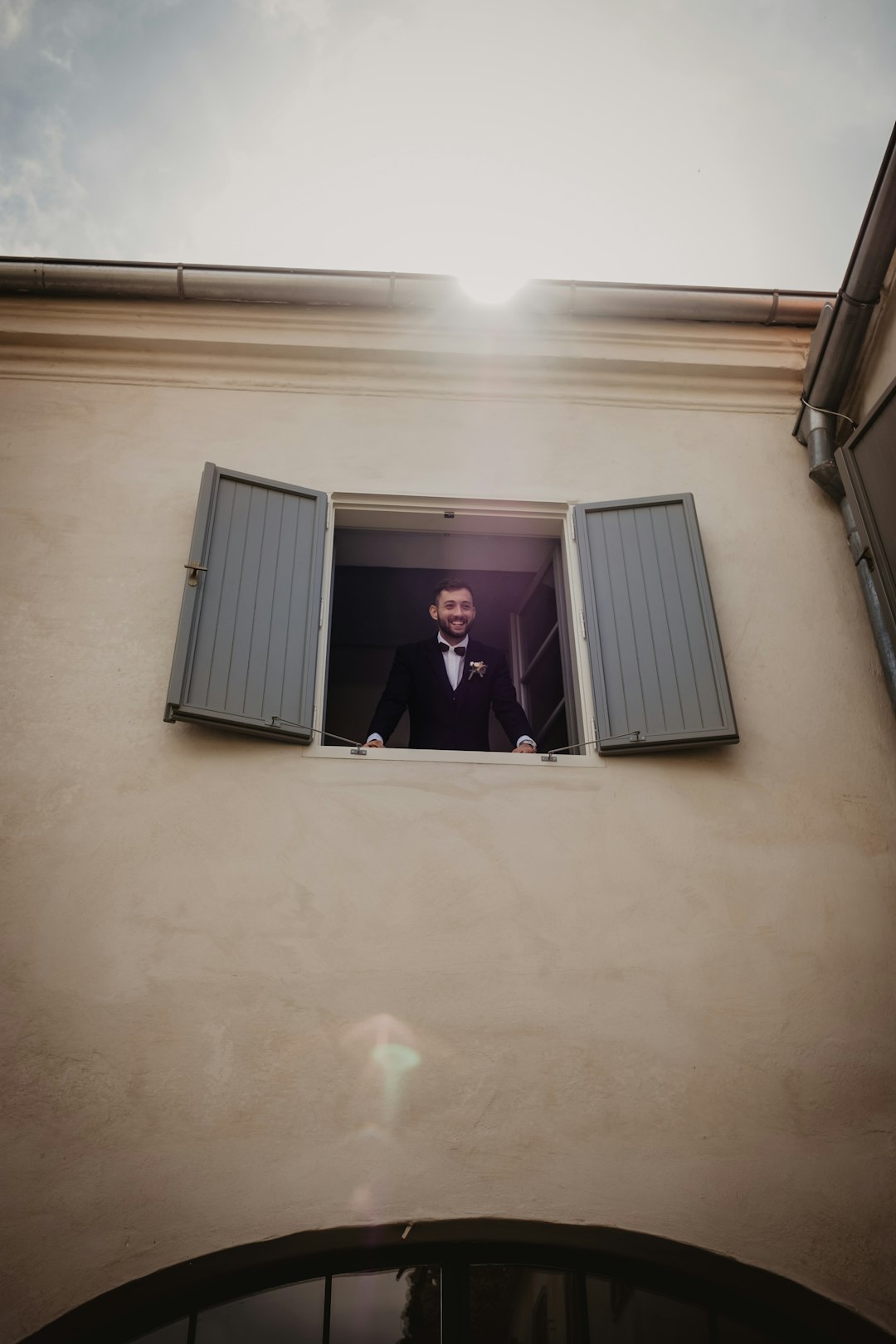 man in black suit jacket standing near white window blinds