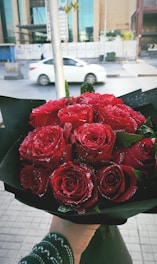 A Luxeora Flowers delivery driver carefully carrying a beautifully wrapped bouquet through a sunlit Dubai street.