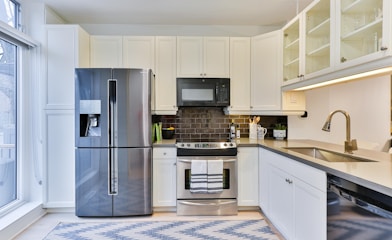 silver french door refrigerator beside white wooden kitchen cabinet