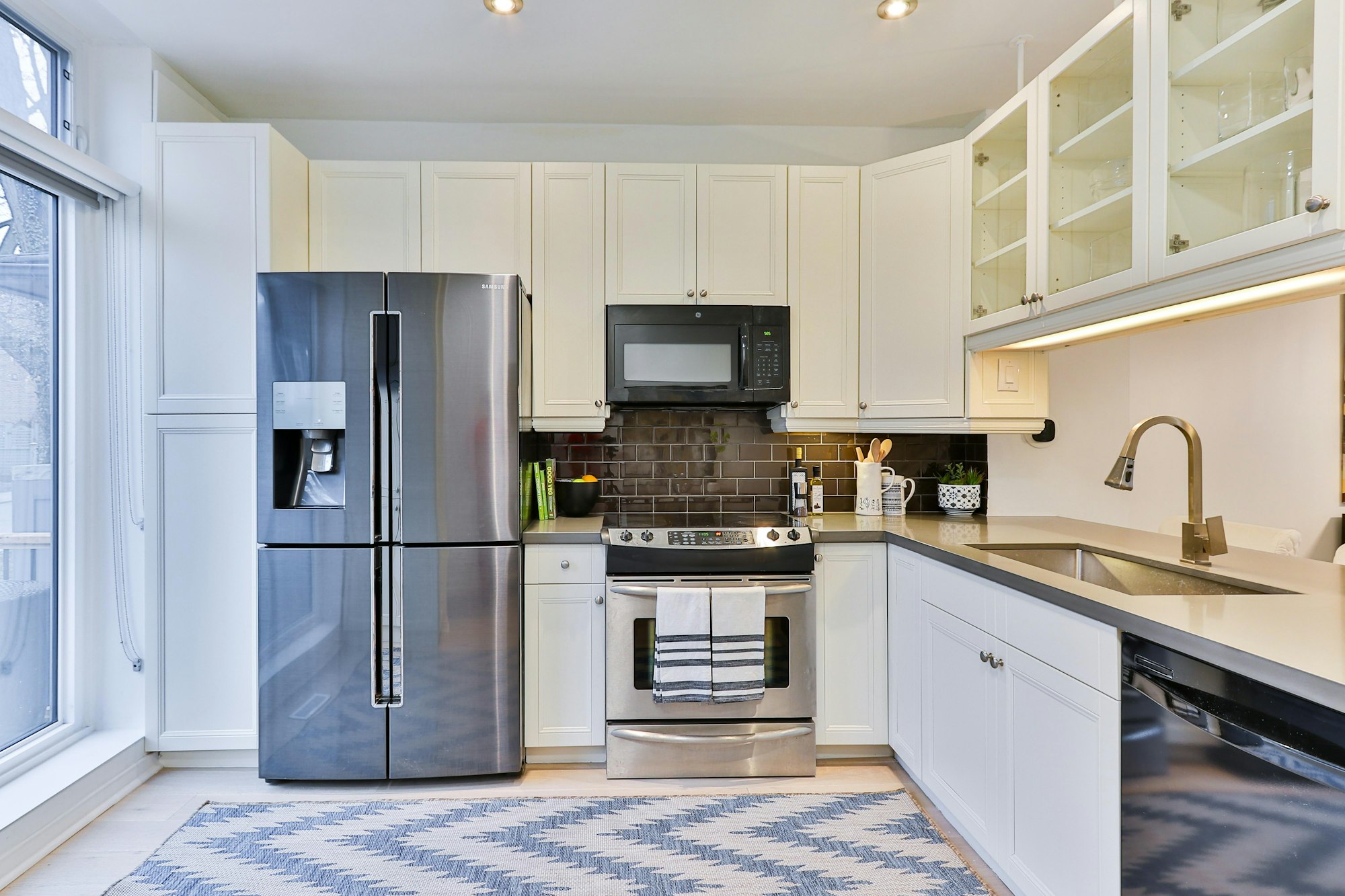 The view of a kitchen showcases stainless steel appliances and white cabinets.