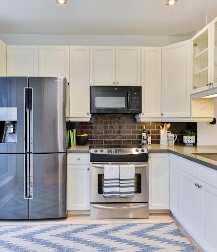 silver french door refrigerator beside white wooden kitchen cabinet